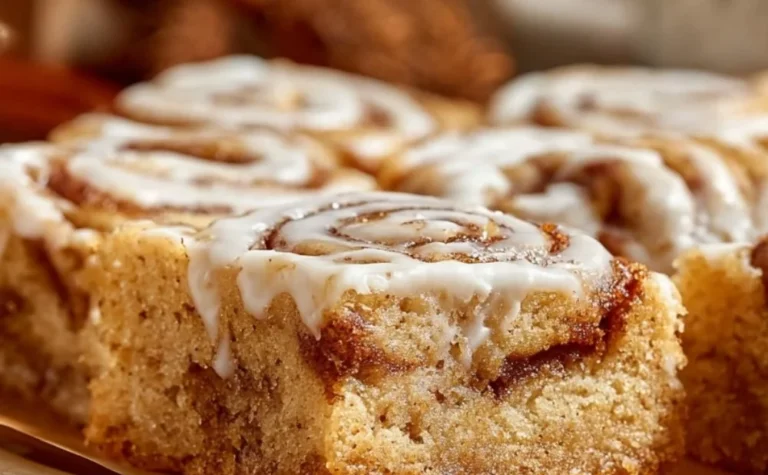 Delicious cinnamon roll cookie bars topped with icing on a white plate.